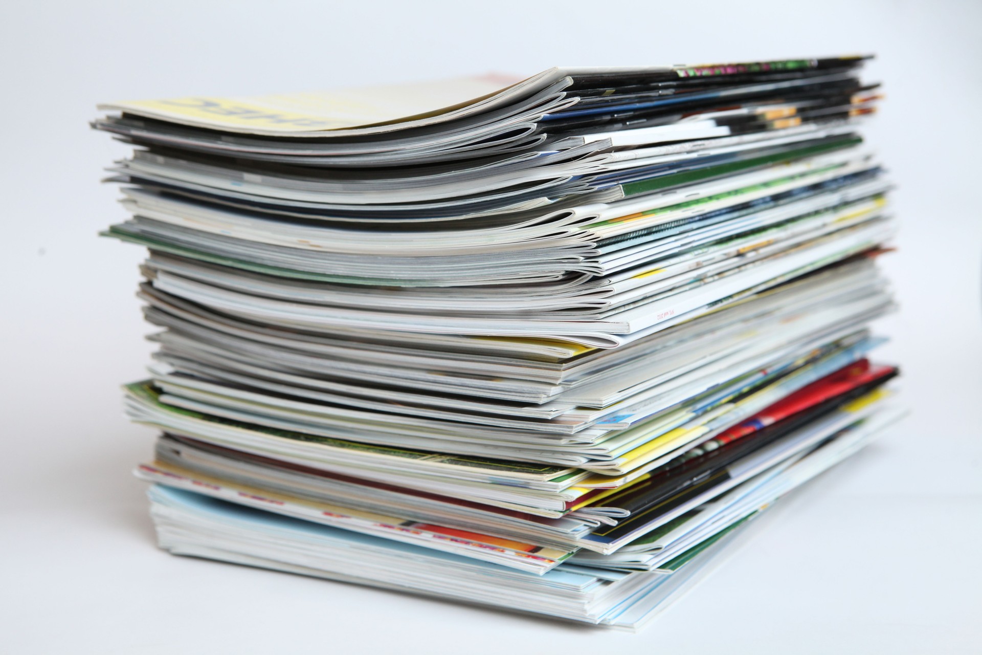 A large stack of printing magazines on a white background. Lots of different publications.